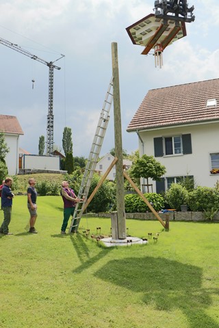 Gerhard Stolz (an der Leiter) und ein Helfer verfolgen gespannt, wie das Dach auf den Mast gesetzt wird.