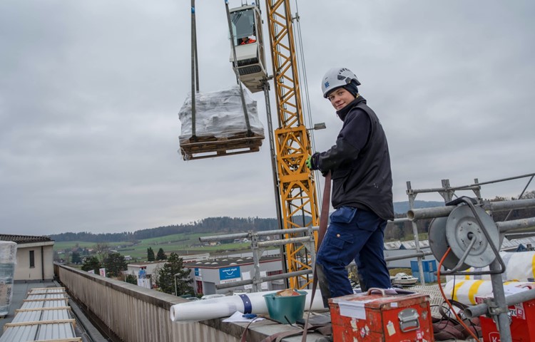 Fabio Neidhart in luftiger Höhe in Oberohringen. Gerade werden mit einem grossen Mobilkran Kalzip-Profilbleche aufs Dach gehievt. Fabio Neidhart in luftiger Höhe in Oberohringen. Gerade werden mit einem grossen Mobilkran Kalzip-Profilbleche aufs Dach gehievt.