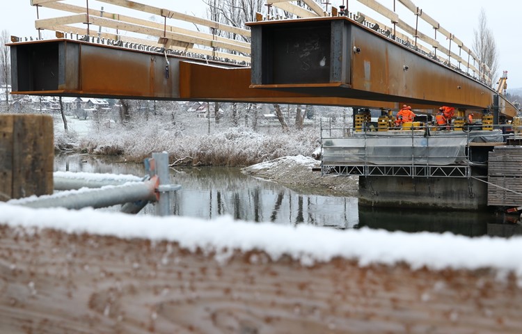 Erst am Schluss wird die im Endausbau sichtbare Konstruktion aus Cortenstahl auf die Brückenpfeiler abgesetzt. Die Elemente werden am Ufer geschweisst und eingeschoben. Auf dem Träger rechts ist eine Markierung angebracht. Mit Laser wird gemessen, ob sich die Konstruktion innerhalb der berechneten Bahn bewegt. Erst am Schluss wird die im Endausbau sichtbare Konstruktion aus Cortenstahl auf die Brückenpfeiler abgesetzt. Die Elemente werden am Ufer geschweisst und eingeschoben. Auf dem Träger rechts ist eine Markierung angebracht. Mit Laser wird gemessen, ob sich die Konstruktion innerhalb der berechneten Bahn bewegt.