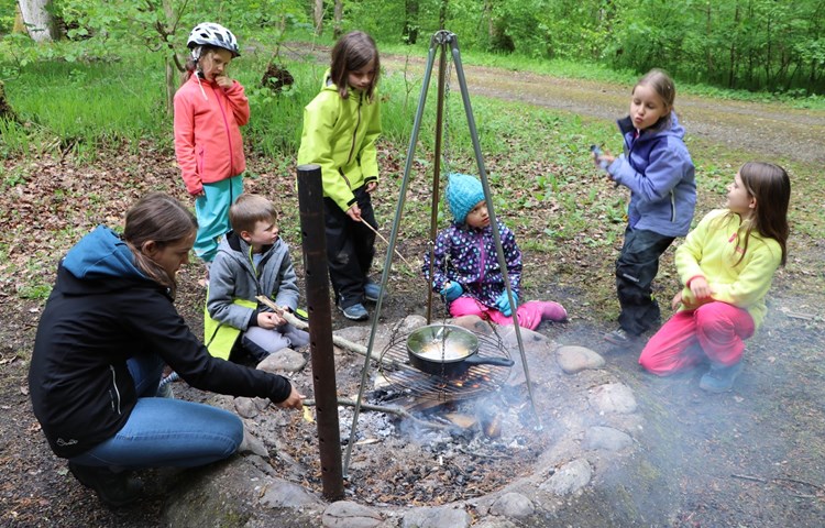 Die Kinder warten gespannt, bis sich die ersten Maiskörner in Popcorn verwandeln. Damit das Feuer nicht ausgeht, muss immer mal wieder ein Holzscheit nachgelegt werden. Die Kinder warten gespannt, bis sich die ersten Maiskörner in Popcorn verwandeln. Damit das Feuer nicht ausgeht, muss immer mal wieder ein Holzscheit nachgelegt werden.